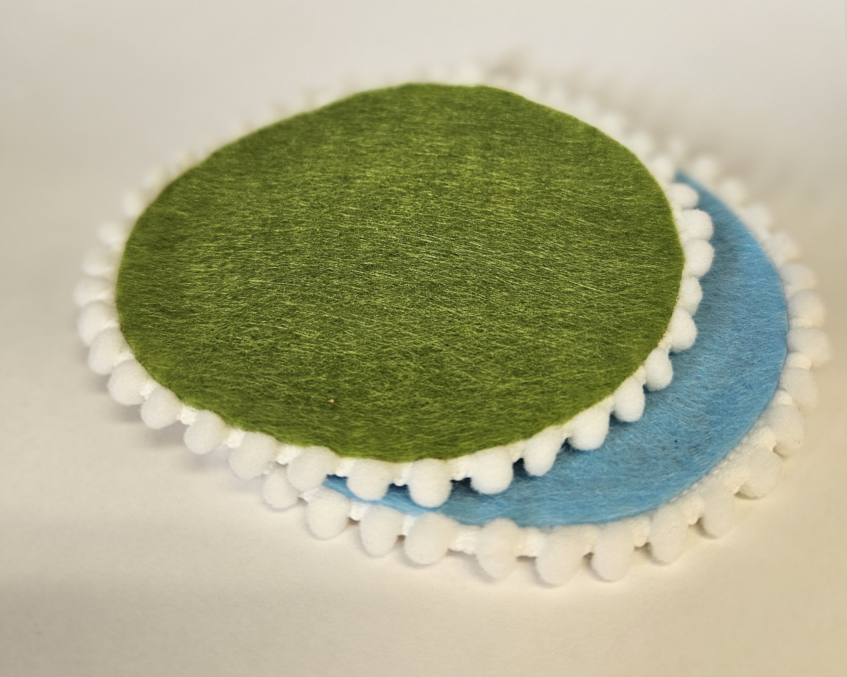 two coasters decorated with felt and pom-poms