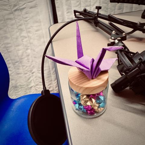 Origami bird resting on jar of origami stars and sitting in audio booth
