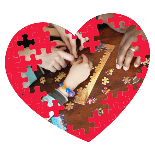 Red heart shape puzzle with hands putting together puzzle pieces