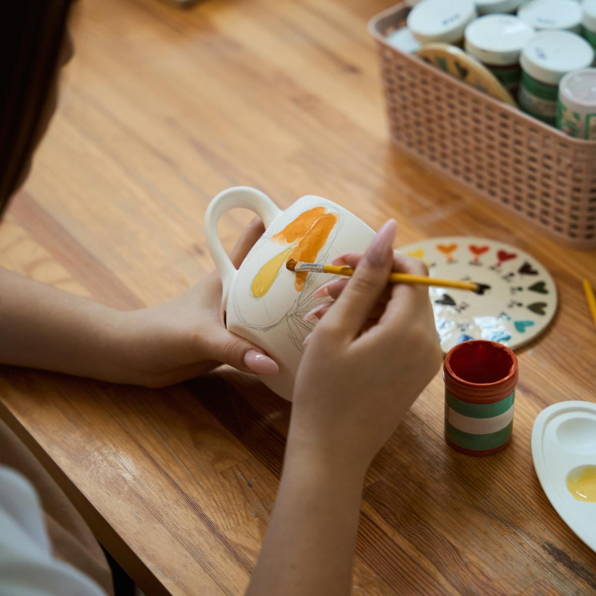 person painting pottery